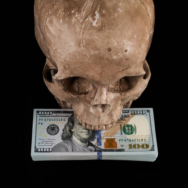 Μοντέλο ανθρώπινου κρανίου και ένα πακέτο αμερικάνικα δολάρια. - Φωτογραφία, εικόνα