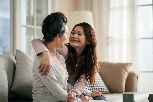 Asijské dospělé dcery a starší matky sedí na gauči doma s příjemnou konverzaci - Fotografie, Obrázek