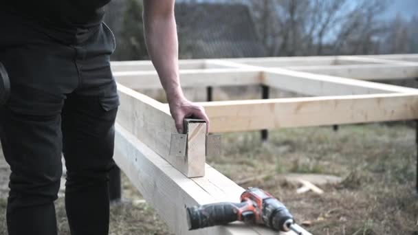 Man bouwend houten frame huis op paalfundering. Timmerman het installeren van meubels voor houten plaat, met behulp van hamer. Timmermansconcept. - Video