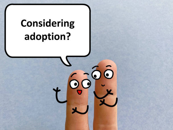 Zwei Finger sind als zwei Personen dekoriert. Einer von ihnen fragt einen anderen, ob er eine Adoption in Betracht zieht. - Foto, Bild