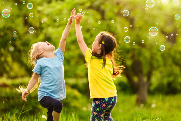 Dos niñas están soplando burbujas de jabón, rodaje al aire libre
 - Foto, imagen