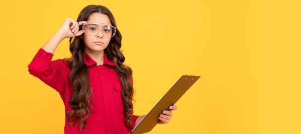 Çok zeki görünüyorsun. Genç kız gözlük takıyor. Çocuk sarı arka plandaki dosyalara not alıyor. Koruyucu gözlüklü, yatay poster tasarımlı bir çocuk geliştirici. Başlık, kopyalama alanı - Fotoğraf, Görsel