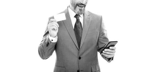 hombre de negocios grizzled recortado en tarjeta de retención de traje y teléfono celular para pagar en línea aislado en blanco, negocio ágil. - Foto, imagen
