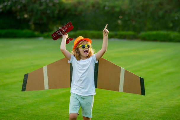 Happy childhood. Portrait of child with toy paper wings outdoor. Success, creative and start up concept - Photo, Image
