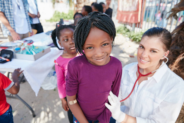 Les enfants en bonne santé sont des enfants heureux. Portrait d'infirmières bénévoles donnant des examens aux enfants défavorisés - Photo, image
