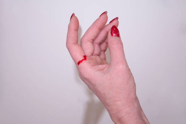 γυναίκα έκοψε το χέρι της με χαρτί και δώρο τυλίγοντας κόκκινο αίμα στο χέρι της. Υψηλής ποιότητας φωτογραφία - Φωτογραφία, εικόνα