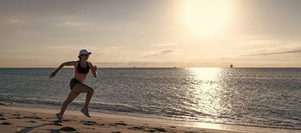 Woman run and jump on sea beach. Active woman runner in sportswear run on beach sand along seaside, running - Photo, Image