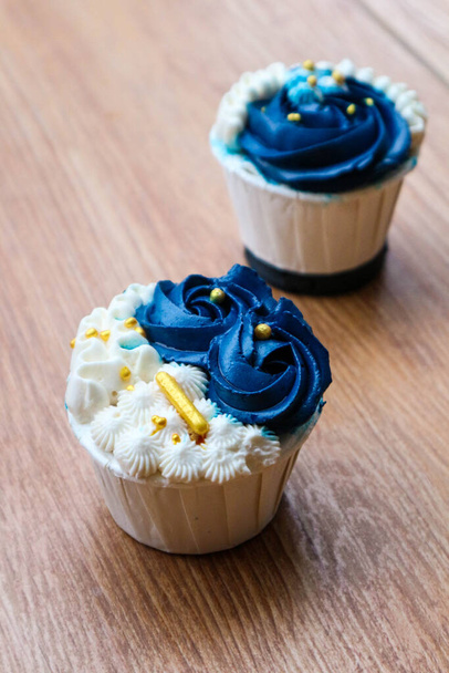 Luxurious and elegant cupcakes, with white cream and navy blue with gold sprinkles. It has a sweet and creamy taste. - Foto, immagini