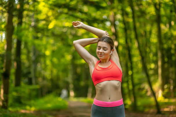 Sportovní dívka cvičení před jogging v parku, protahování svaly venku, pocit zdravý a motivovaný, kopírovat prostor - Fotografie, Obrázek