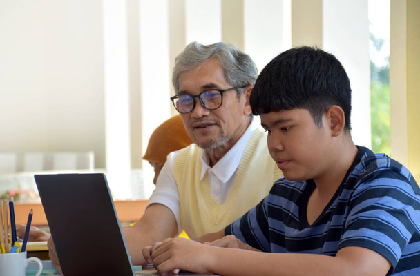 アジア系の少年たちは、部屋の中でアジア系の高齢者の先生の前に座って、学校のプロジェクトの仕事をし、彼らのプロジェクトの仕事、ソフトと選択的フォーカスについて高齢者の先生に耳を傾けます - 写真・画像