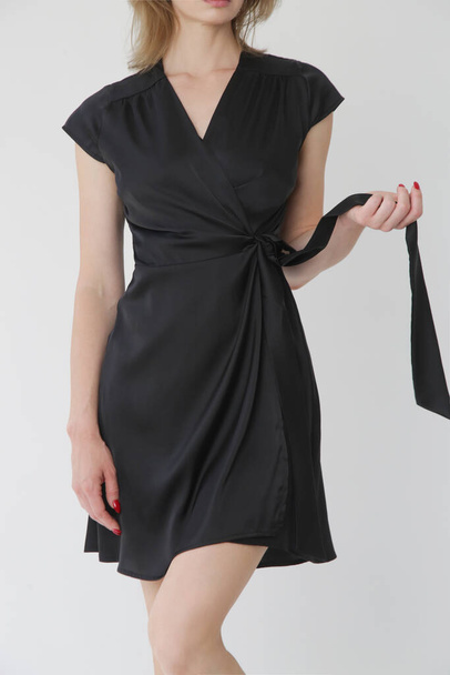Serie of studio photos of young female model in black silk satin wrap mini dress. - Photo, Image