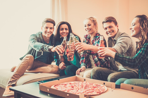 Amigos multiétnicos con pizza y botellas de bebida
 - Foto, imagen