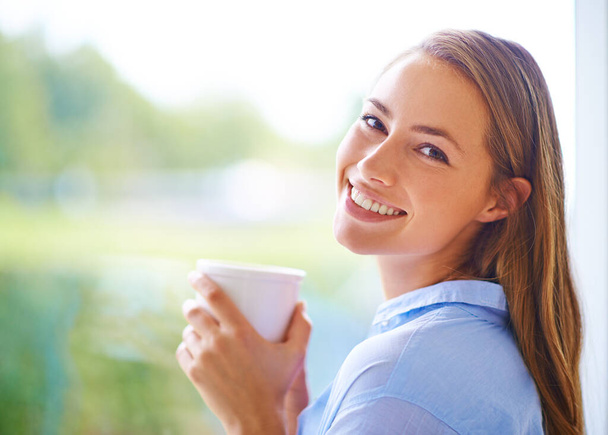 Rilassati con una bella tazza di tè. Ritratto ritagliato di una giovane donna che prende il tè in piedi vicino a una finestra - Foto, immagini