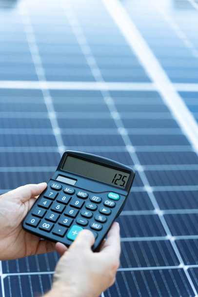 Alguien está calculando los ahorros de usar un sistema de panel solar con una calculadora - Foto, imagen
