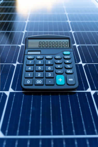 Image of a calculator on a solar panel representing the concept of saving energy with renewable energy - Photo, Image