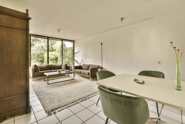uma sala de estar com piso em azulejo branco e grandes portas de madeira que levam ao pátio exterior, que está aberto - Foto, Imagem