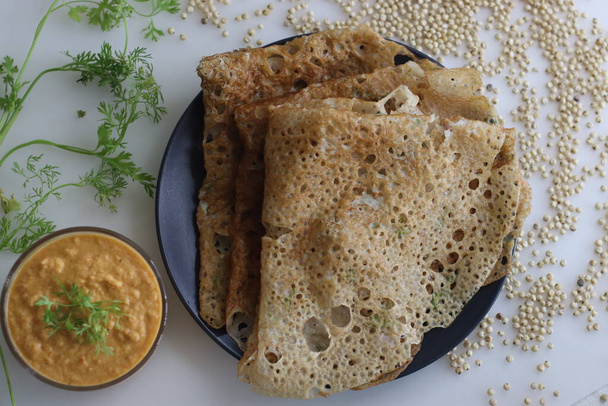 Instant Jowar dosa on nopea ja helppo intialainen aamiaisruokalaji, joka on valmistettu jowar-jauhoista sekoittamalla se veteen ja keittämällä esilämmitetyllä non stick pannulla. Tarjoillaan kookos kylmä mausteinen mausteinen mauste - Valokuva, kuva