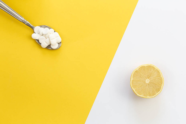 Prášky a citron na žlutém pozadí, plochý ležel, vitamín C koncept. - Fotografie, Obrázek