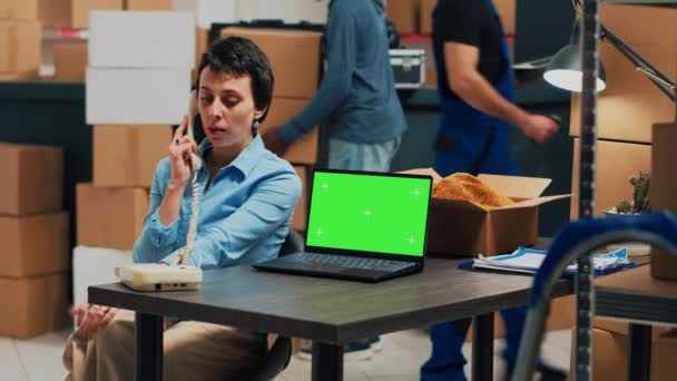 İşyeri sahibi sabit hattan arıyor. Laptop 'ta yeşil ekran var. Telefon kablosuyla eşya kutularını gönderiyor. Mal teslimatında çalışan bir kadın, tedarik zinciri.. - Video, Çekim