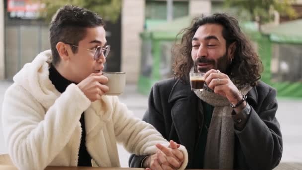 Vídeo en cámara lenta de una elegante pareja gay hablando mientras bebe café en una cafetería - Metraje, vídeo
