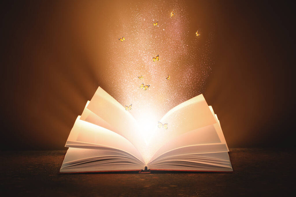 Libro magico aperto con bagliore e farfalle volanti su sfondo scuro - Foto, immagini