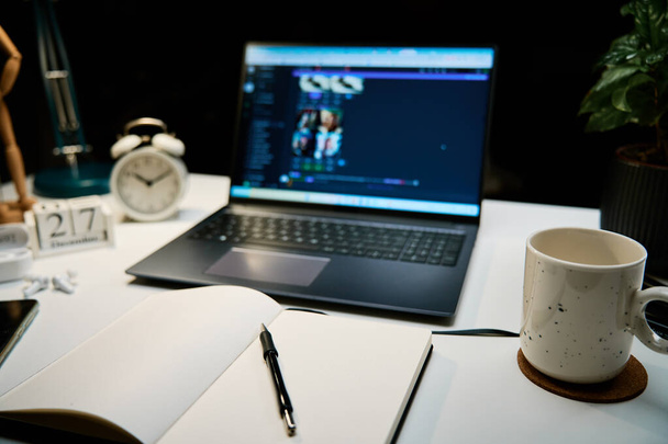 Työpaikka kotitoimistossa kannettava tietokone, kuppi kahvia ja lamppu pöydällä yötyötä - Valokuva, kuva