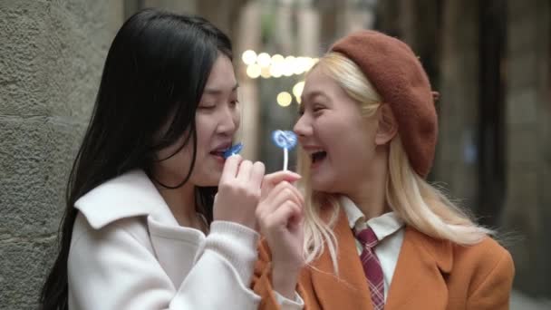 Zpomalení videa asijské lesbičky pár baví při jídle cukroví ve městě ulici - Záběry, video