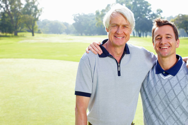 Ojciec i syn uśmiechnięci. Portret ojca i syna na polu golfowym stojących z rękami dookoła i uśmiechniętymi - Zdjęcie, obraz