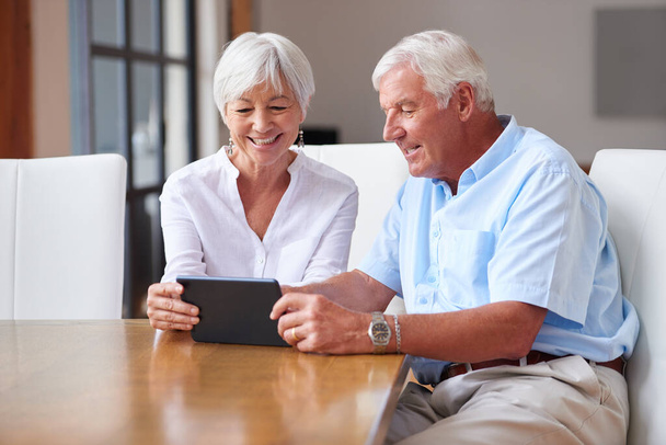 Hay mucha más información disponible gracias a la tecnología. una pareja de personas mayores usando una tableta digital en casa - Foto, imagen