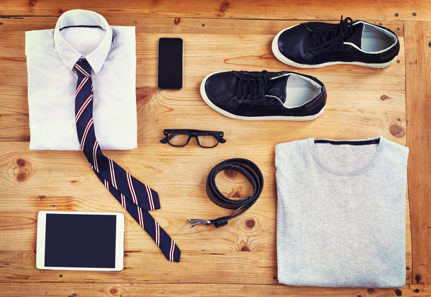 Kit for the modern man. High angle shot of a smart and a casual outfit with digital devices laid out on a wooden table - Photo, Image
