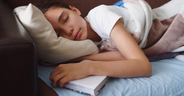 Крупный план 4k кадры девушка спит с книгой под подушкой - она выпрямляет одеяло и ложится более комфортно. - Кадры, видео