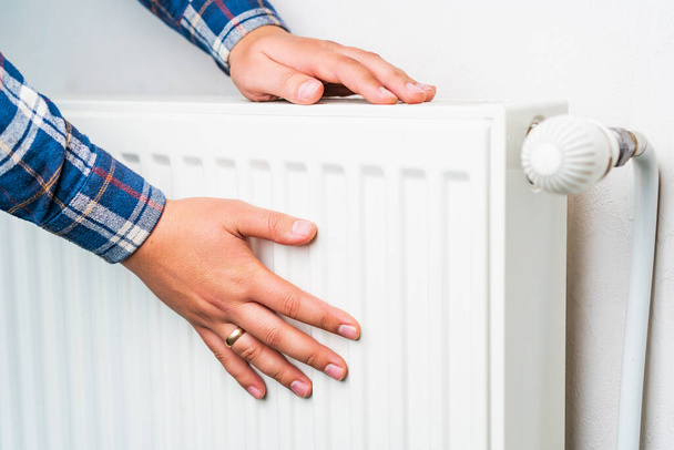 Hands on the radiator of the heating system, selective focus. Background with copy space - Photo, Image