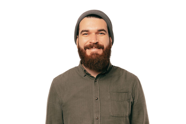 Portrait of young bearded smiling man looking confident at the camera over white backgorund wearing hat. - Foto, Imagen