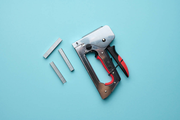 Household manual stapler and staples on a blue background, top view - Photo, Image