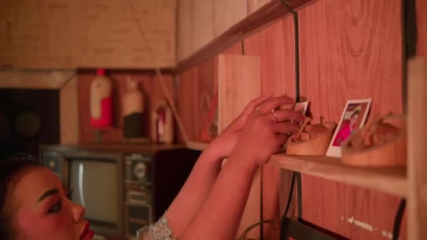 Indonéská žena vezme fotografii a drží ji v rukou, zatímco vidí se šťastnou tváří před dřevěnou stěnou ve svém pokoji - Záběry, video