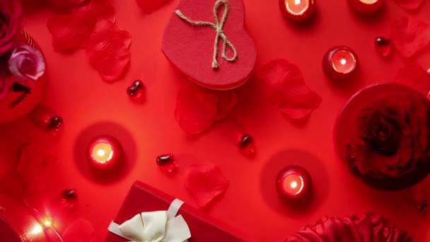 Ystävänpäivä romanttinen koristelu ruusuilla, boxed lahjoja, kynttilöitä, punaisella taustalla pöydällä. Top näkymä, kopioi tilaa
. - Materiaali, video