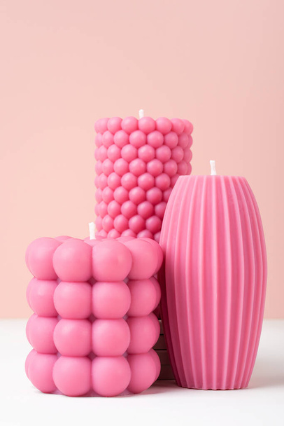 Ручної роботи з оливкового воску різні форми рожевого кольору свічки на дуотоновому пастельному рожево-білому тлі. Стабільна веганська свічка, натуральні матеріали. Мінімалістична, сучасна фотографія. Копіювати простір. вертикальний - Фото, зображення