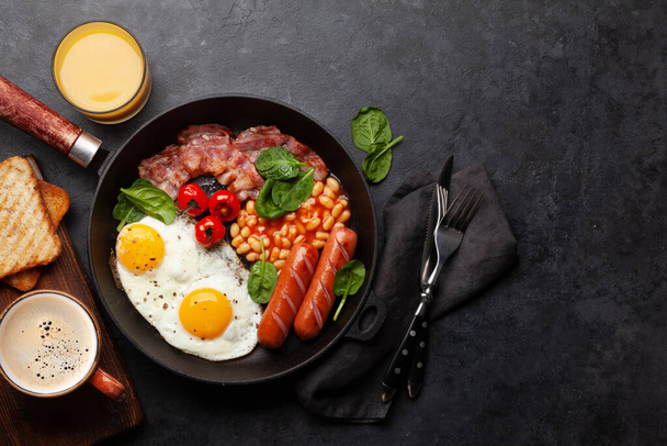 Desayuno inglés con huevos fritos, frijoles, tocino y salchichas. Vista superior plano con espacio de copia - Foto, Imagen