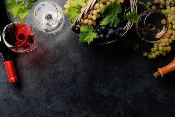 Copas de vino blanco, rosa y tinto, botellas y uva en cesta. Piso con espacio de copia - Foto, imagen