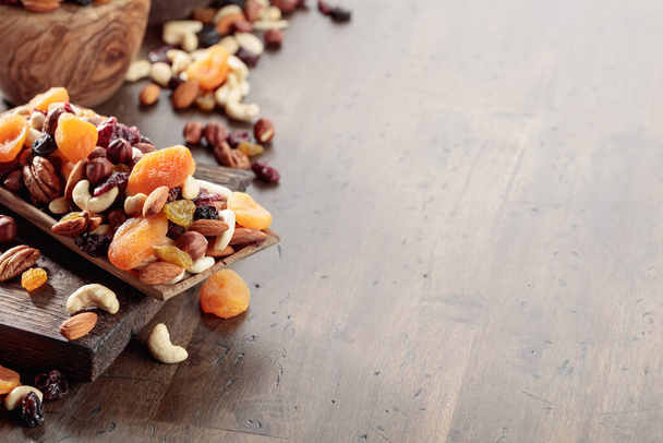 Směs ořechů a sušeného ovoce na starém dřevěném stole. Prezentované meruňky, rozinky, vlašské ořechy, lískové oříšky, kešu, ořechy a mandle. Kopírovat prostor. - Fotografie, Obrázek
