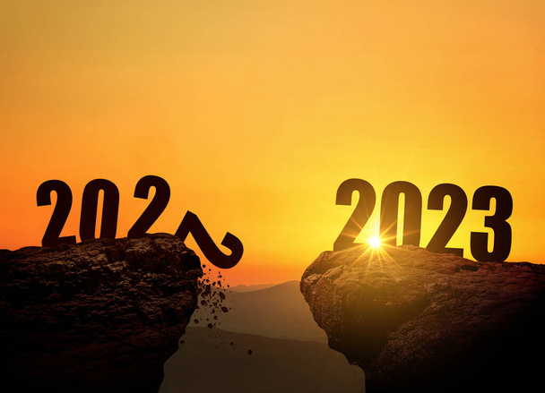 Новогодняя ночь 2023 года на горе на закате, концепция. 2022 и 2023 на утёсе на рассвете, творческая идея. 2022 падает в пропасть. Свободное пространство для дизайна - Фото, изображение