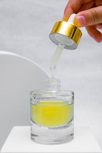 Bottle pipette dropper and Liquid yellow-orange retinol or vitamin c gel or serum on a white background - Fotoğraf, Görsel