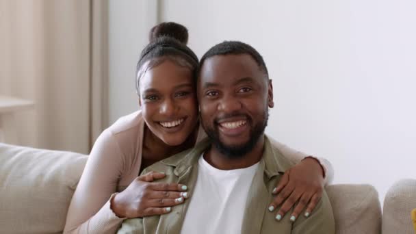 Καλές σχέσεις. Κοντινό πορτρέτο του νεαρού χαρούμενου αφροαμερικανού άνδρα και γυναίκας που χαμογελά στην κάμερα μαζί, αγκαλιάζοντας στο σπίτι, αργή κίνηση, ελεύθερο χώρο - Πλάνα, βίντεο