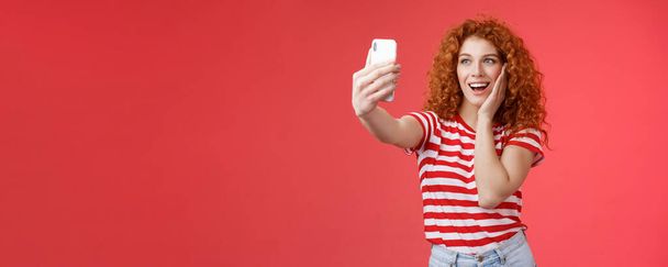 Τρόπος ζωής. Μοντέρνο χαριτωμένο κοκκινομάλλα σγουρά θηλυκό καλοκαιρινό t-shirt ρεκόρ βίντεο social media από την πολυτέλεια τροπικά αποφασιστικά ταξίδια διακοπές στο εξωτερικό λάβει selfie κρατήσει smartphone θέτουν ανόητη φωτογραφία κόκκινο - Φωτογραφία, εικόνα