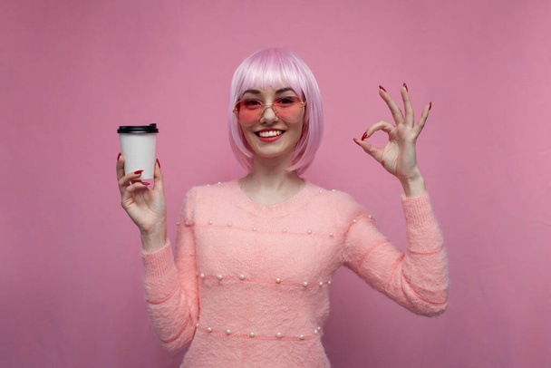 young girl with pink hair holding coffee and showing ok sign, hipster with colored hairstyle - Photo, image