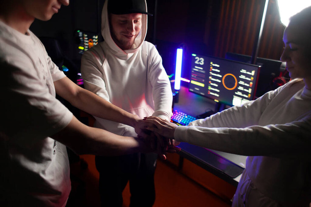 młody zespół komputerowy omawianie strategii razem i trzymanie się za ręce, zespół utworzony przed grą w klubie komputerowym - Zdjęcie, obraz