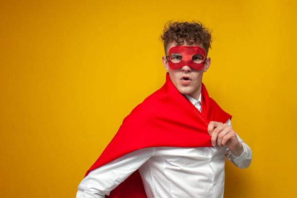 young guy in a shirt put on a super hero costume on a yellow background, the worker turned into super man, concept - Photo, Image