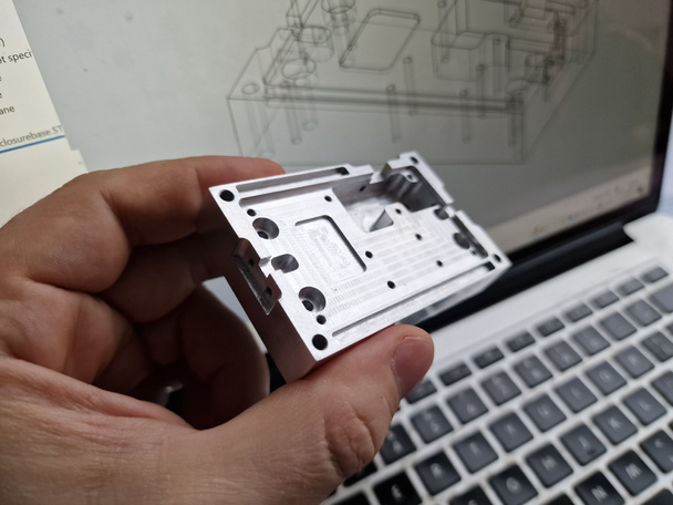 Mechanical engineer hand holding CNC milled custom designed project in front of computer screen and drawings - Φωτογραφία, εικόνα