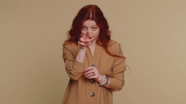I am watching you. Caucasian woman in blouse pointing at her eyes and camera, show I am watching you gesture, spying on someone. Young adult redhead girl isolated alone on beige studio wall background - Séquence, vidéo