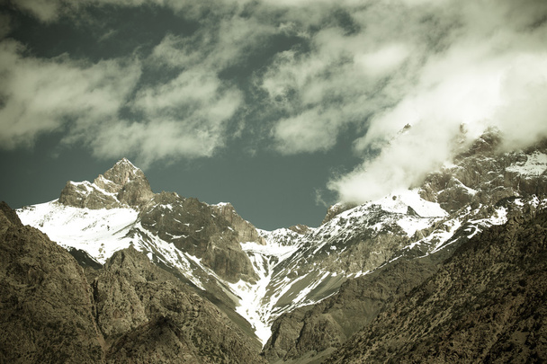 Clouds over the snow-covered tops of the rocks. Landscape. Toned - Photo, Image